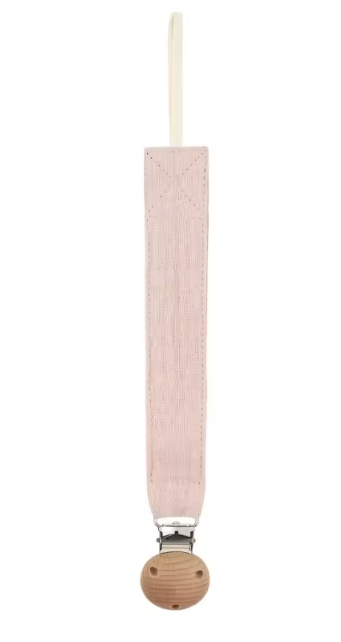 Attache-sucette en tissu rose pâle, de forme longue et étroite, avec une boucle en haut et un clip métallique fixé sur une base ronde en bois en bas.