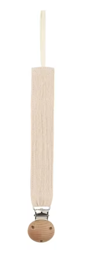 Attache-sucette en tissu beige clair, longue et étroite, avec une boucle en haut et un clip métallique fixé sur une pièce ronde en bois.