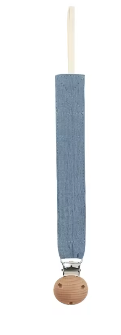 Attache-sucette en tissu bleu, de forme longue et étroite, avec une boucle en haut et un clip métallique fixé sur une pièce ronde en bois.