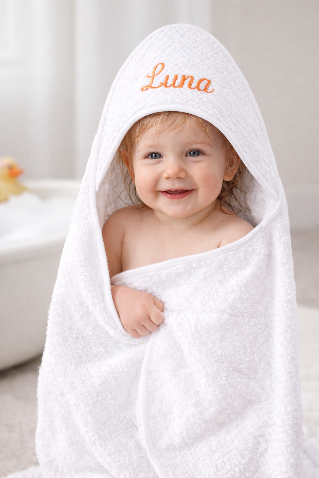 Cape de bain pour bébé en tissu blanc avec capuche triangulaire blanc, vue à plat sur fond clair sur bebe 