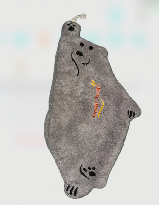 Doudou plat en forme d’ours gris avec visage brodé, pattes dessinées et inscription “Polar Bear” en orange, avec petite attache en tissu en haut.