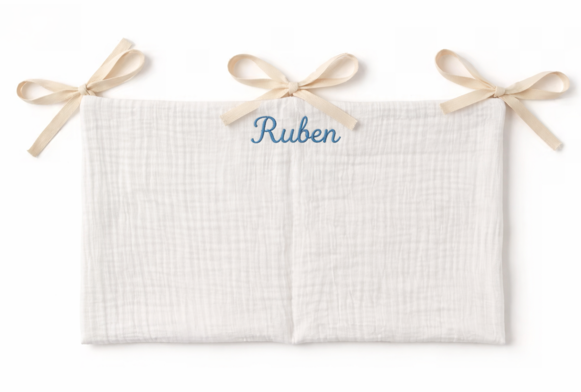 Organisateur de lit bébé en gaze de coton rose avec deux poches, attaché par des liens en ruban beige, avec le prénom Sophie brodé en blanc en haut au centre.