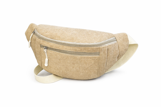 Femme portant un sac banane beige en velours côtelé avec prénom Mounia brodé en marron sur la poche avant