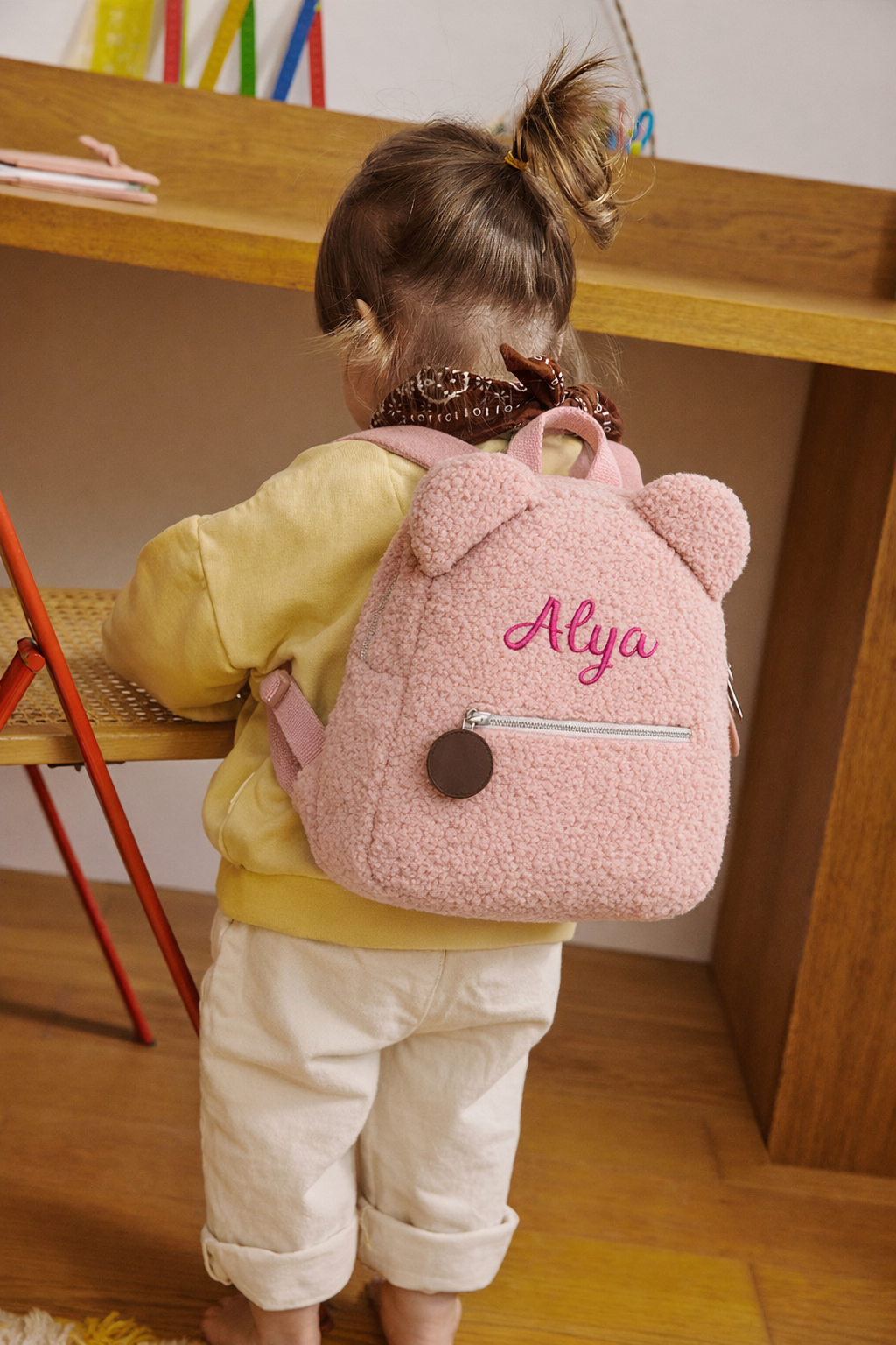 Enfant portant un sac à dos en bouclette rose avec oreilles et prénom brodé, personnalisable