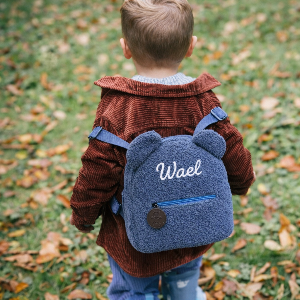 Enfant portant un sac à dos en bouclette rose avec oreilles et prénom brodé, personnalisable bleu 