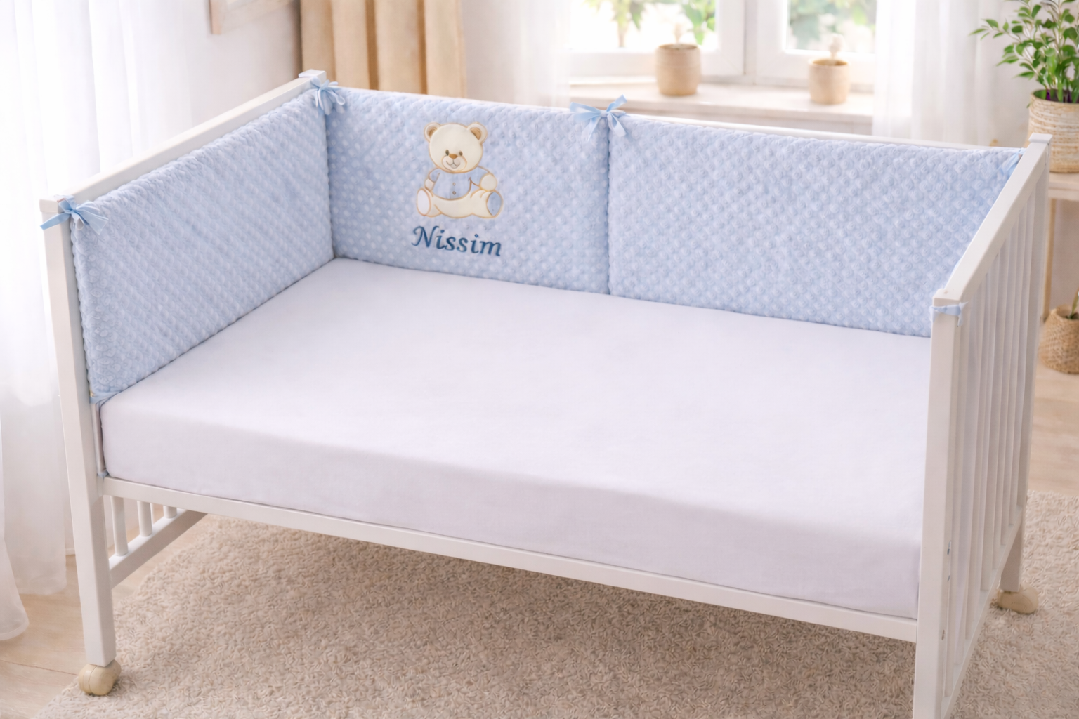 Tour de lit bébé  personnalisé avec prénom brodé , en tissu doux  pilou pilou, installé dans un lit bébé blanc dans une chambre 