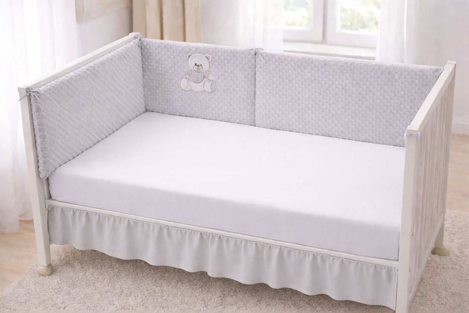 Tour de lit bébé  personnalisé avec prénom brodé , en tissu doux  pilou pilou, installé dans un lit bébé blanc dans une chambre 
