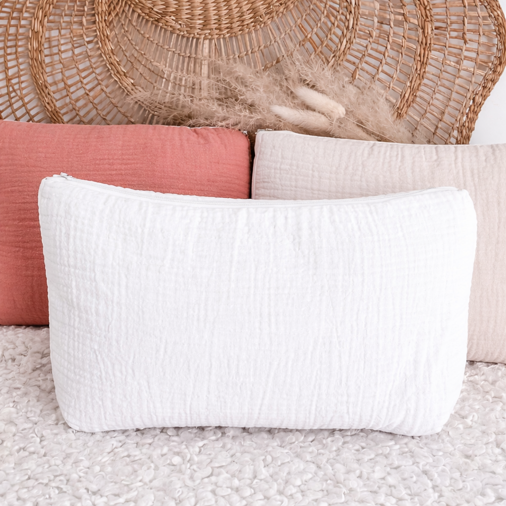 Trousse de toilette blanche en gaze de coton avec texture gaufrée, forme souple et fermeture zippée, idéale pour ranger des produits de beauté ou de voyage.