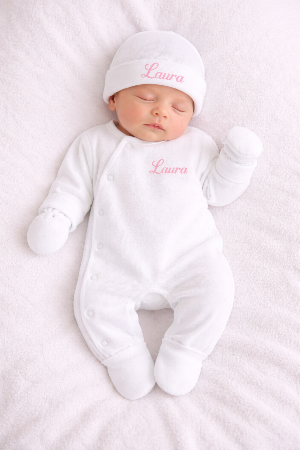 bebe portant Combinaison pour bébé avec fermeture latérale, présentée avec un bonnet et deux moufles assortis.