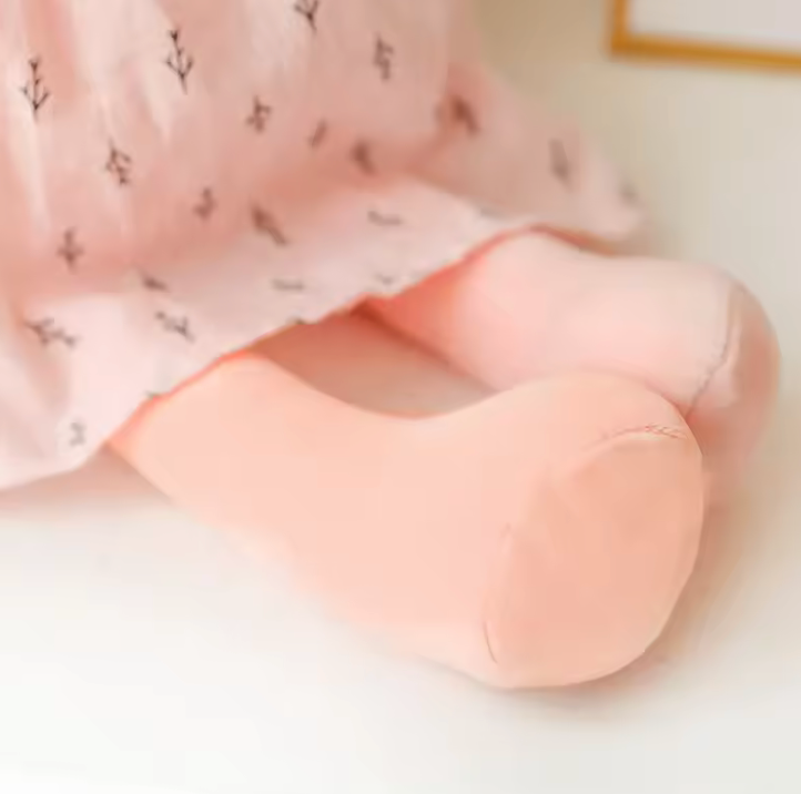 pattes lot Peluche en forme de lapin rose portant une robe, avec de longues oreilles et un nœud sur la tête, assise sur fond blanc.