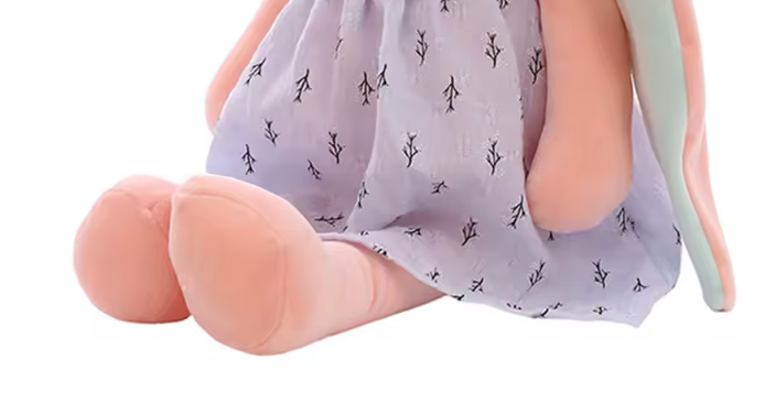 pattes violette Peluche en forme de lapin rose portant une robe, avec de longues oreilles et un nœud sur la tête, assise sur fond blanc. panier 